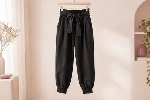 Pantalon noir taille haute avec ceinture nouée amovible, poches latérales et bas de jambes smockés