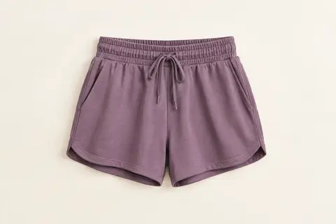 Short de sport femme à taille haute et cordon de serrage, présenté seul sur un fond ivoire lumineux.