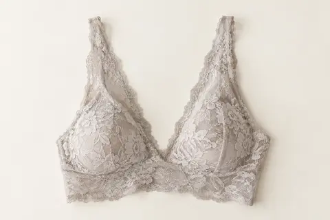 Brassière sans armature en dentelle florale, présentée à plat sur un fond ivoire lumineux