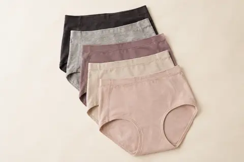 Lot de cinq culottes shorty femme à taille haute, pliées sur un fond ivoire lumineux.