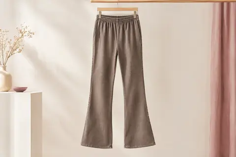 Pantalon de sport bootcut à taille élastiquée présenté seul dans un décor ivoire lumineux.